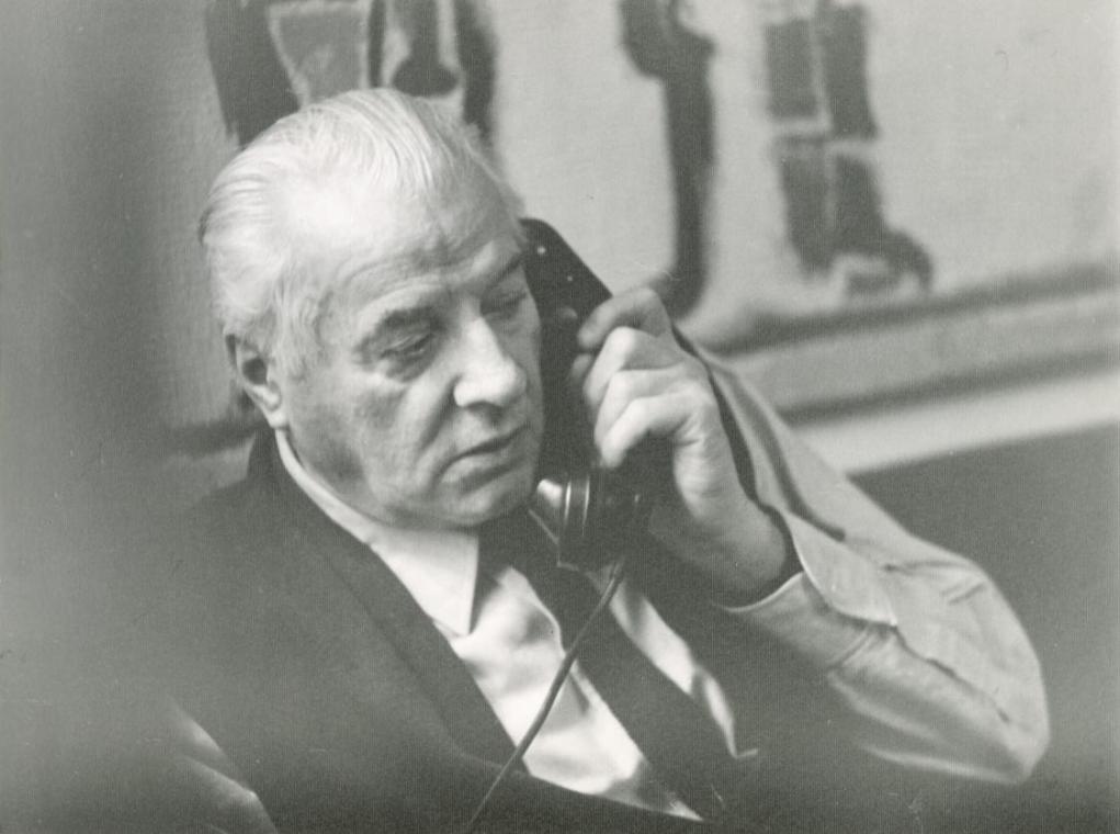 Fritz Wotruba sitzend und telefonierend vor einem Gobelin, der nach einem Motiv von Fritz Wotruba gewebt wurde